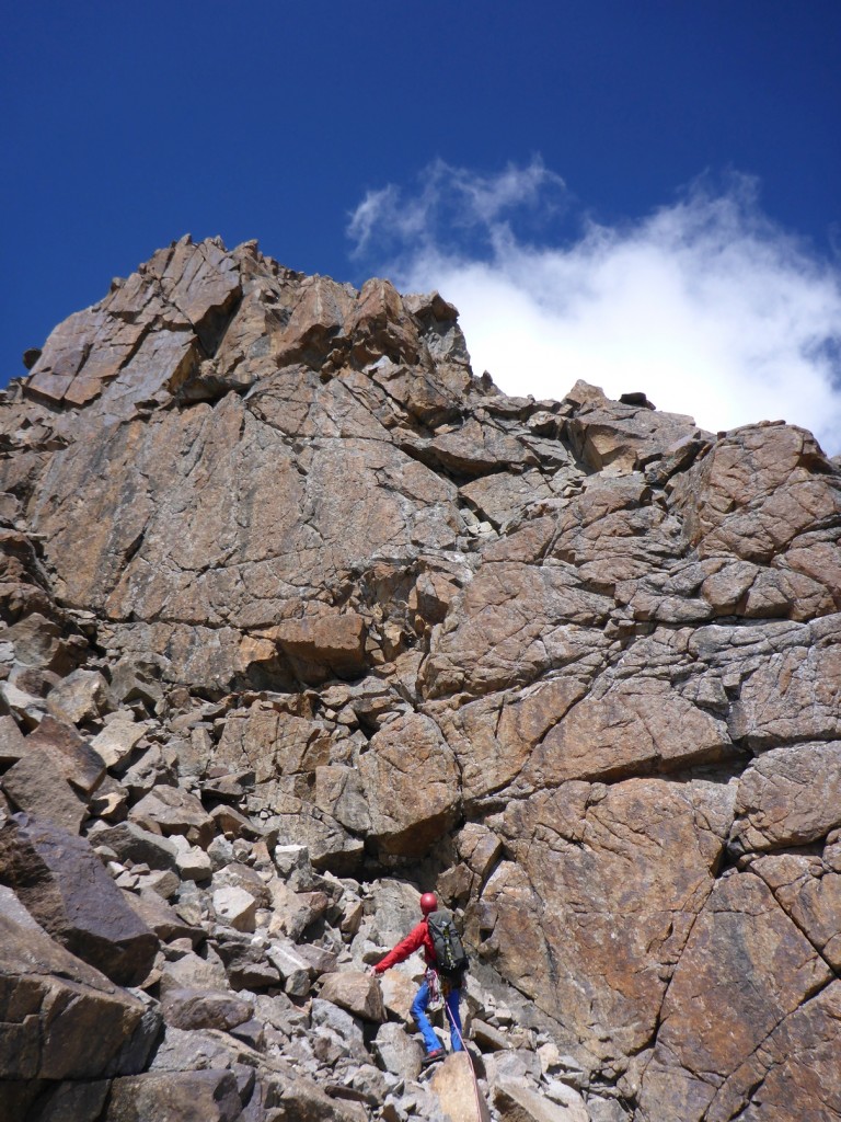 Rock wall high on Peak 4347. I started climbing up the wall above, only to be scared by loose blocks the size of cars threatening to fall off. After retreating carefully back to the scree below the wall, we found a route that ascended up and left, eventually reaching the summit without further difficulty.